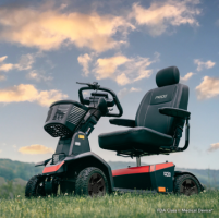 Pride Mobility Scooter in a field, surrounded by grass and trees.