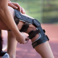 Runner sitting down with an Orthotic knee brace and tennis shoes.